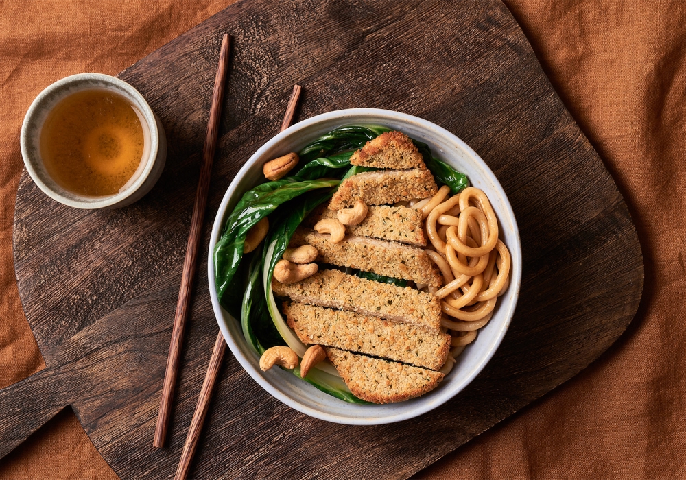 Cotoletta con noodles alla salsa di soia, bok choy (cavolo cinese) e anacardi