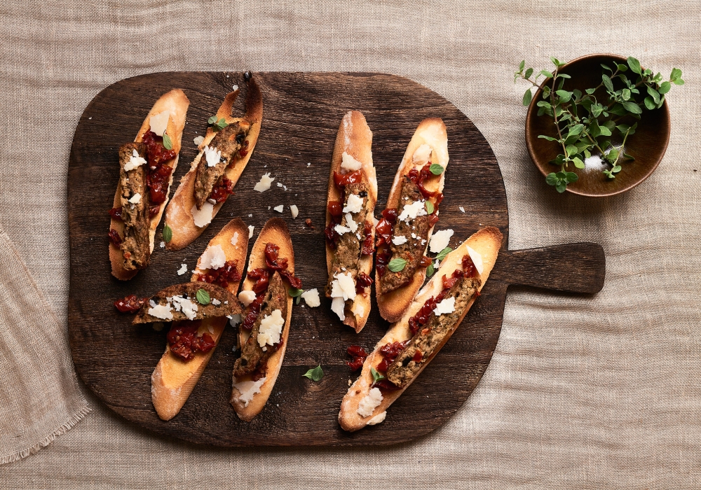 Bastoncini di burger alle melanzane su cialde di pane tostato, tartare di pomodori secchi e scaglie di grana