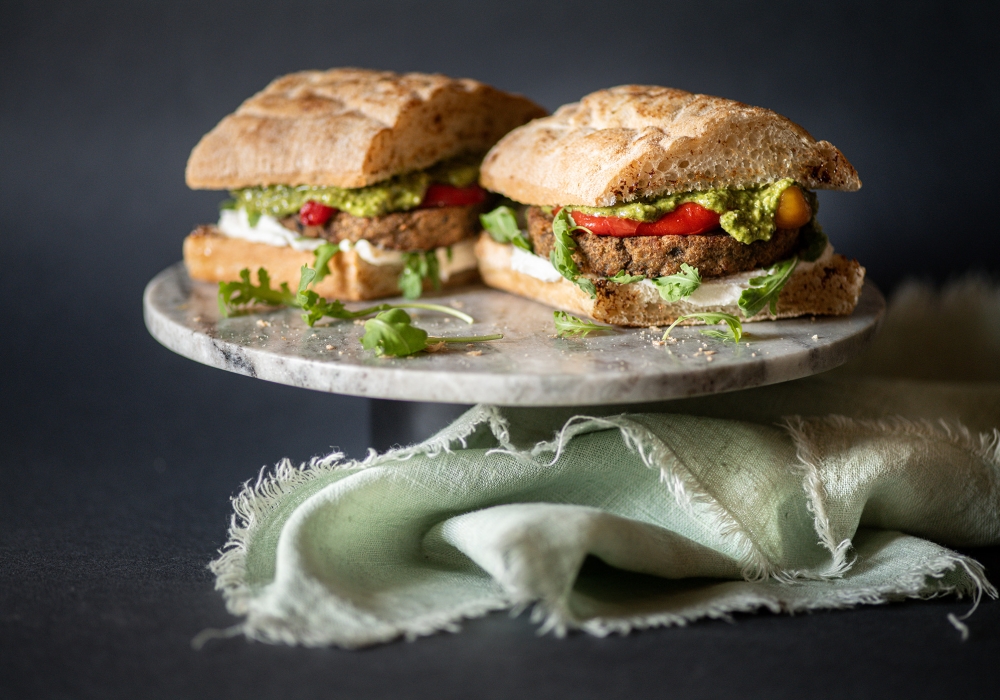 Sandwich con burger di melanzane, pesto, spalmabile vegetale, rucola e peperoni
